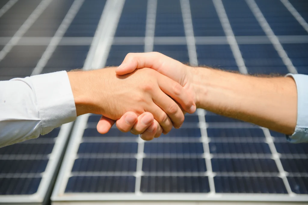 Handschlag mit Solarpanels im Hintergrund